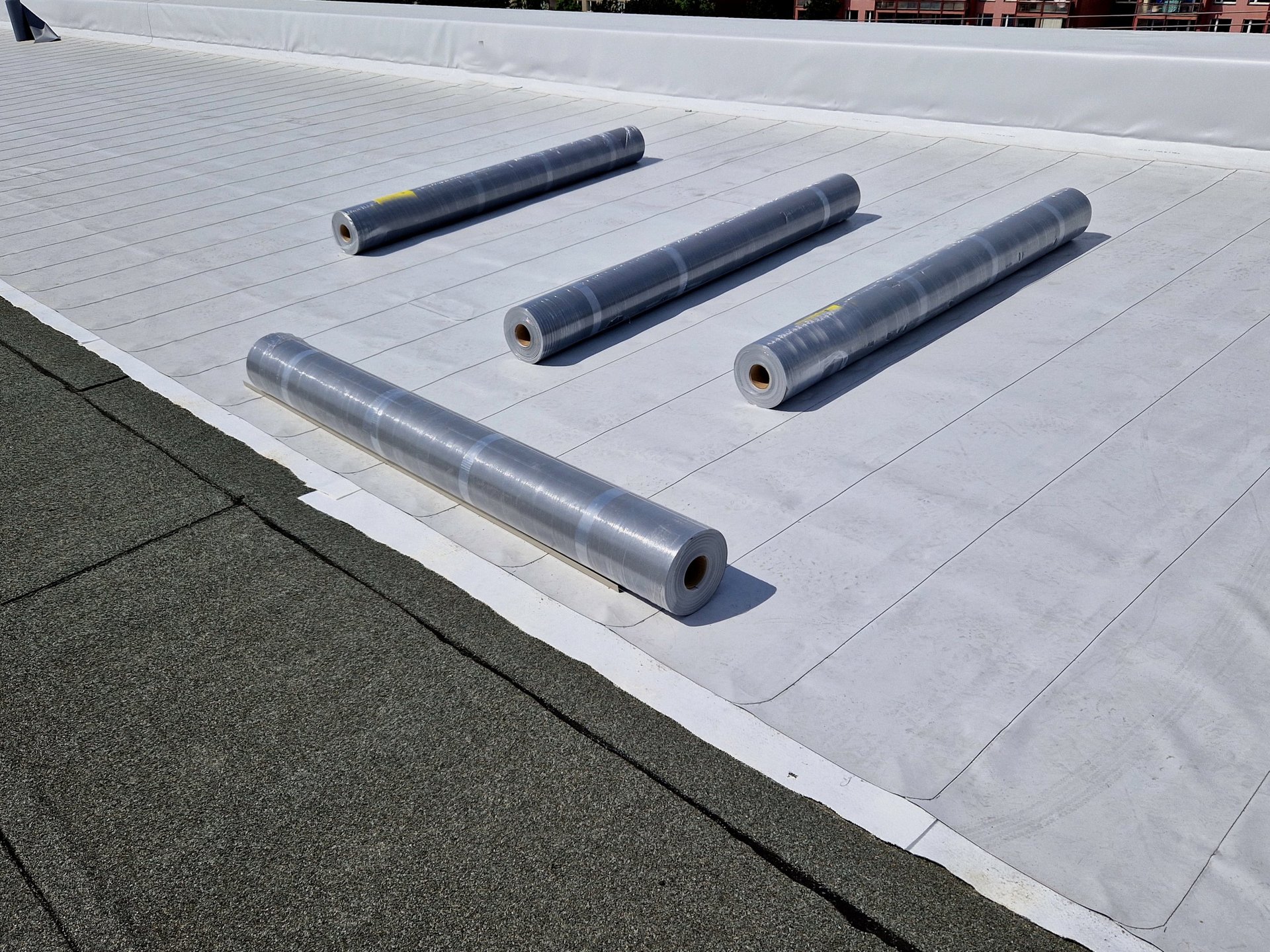 TPO white thermoplastic roofing membrane installation on commercial flat roof, energy efficient reflective white surface