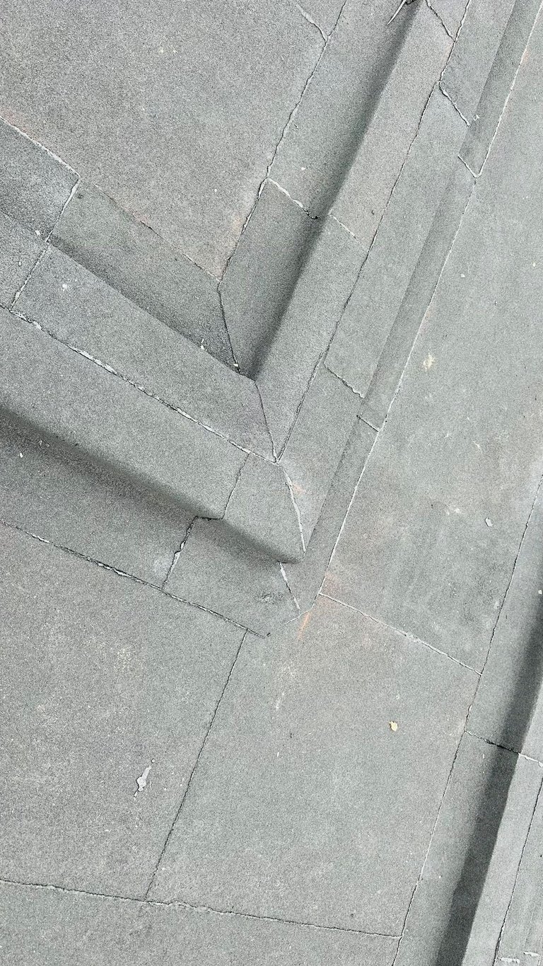 Close-up of gray slate tiles with geometric pattern and shadow lines creating depth and texture