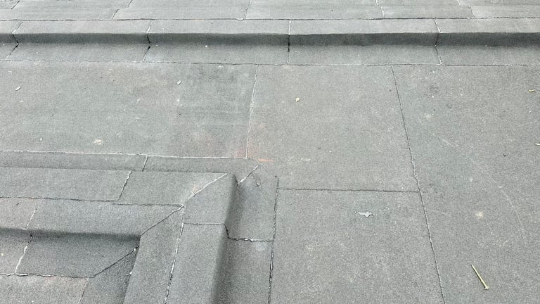 Close-up of gray concrete pavers with visible joints and wear patterns on a surface