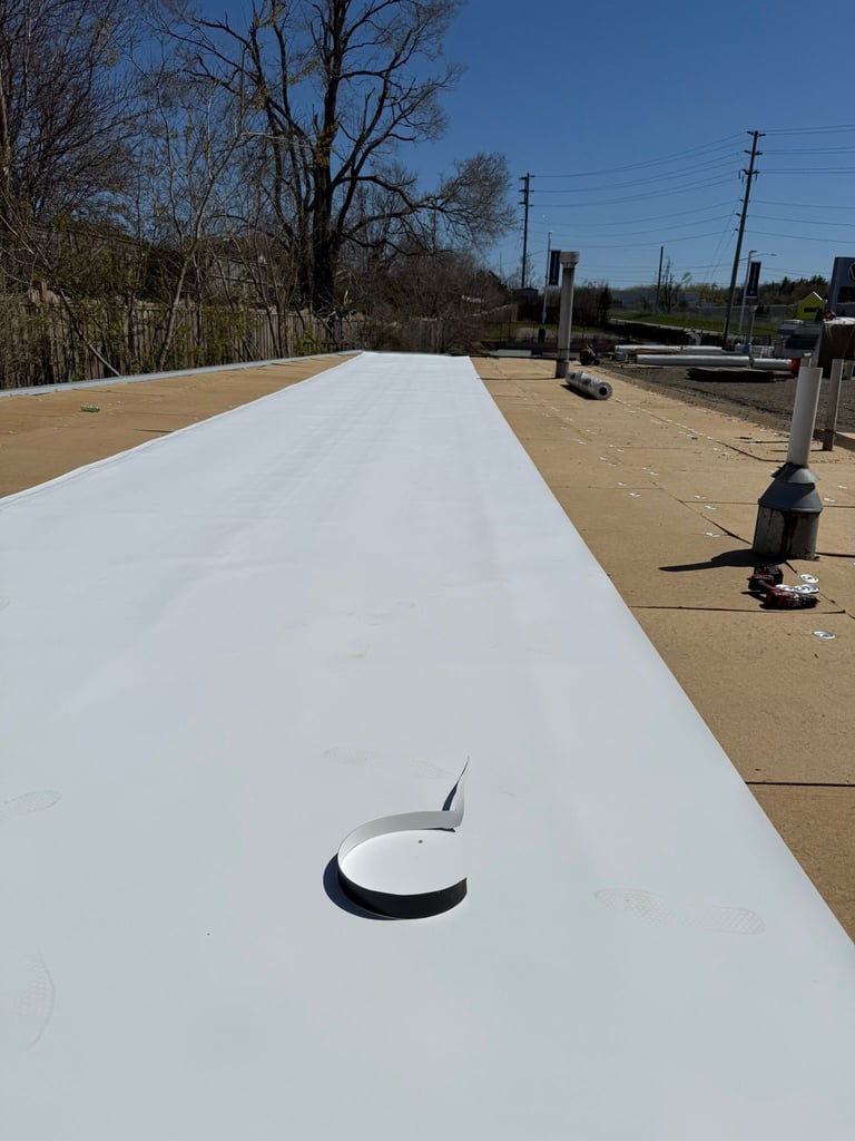 White roof panel with vent opening under construction at a commercial or industrial site with bare ground and metal poles