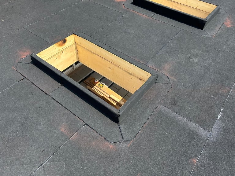 Two wooden roof access boxes with metal flashing installed on a dark asphalt shingle roof surface